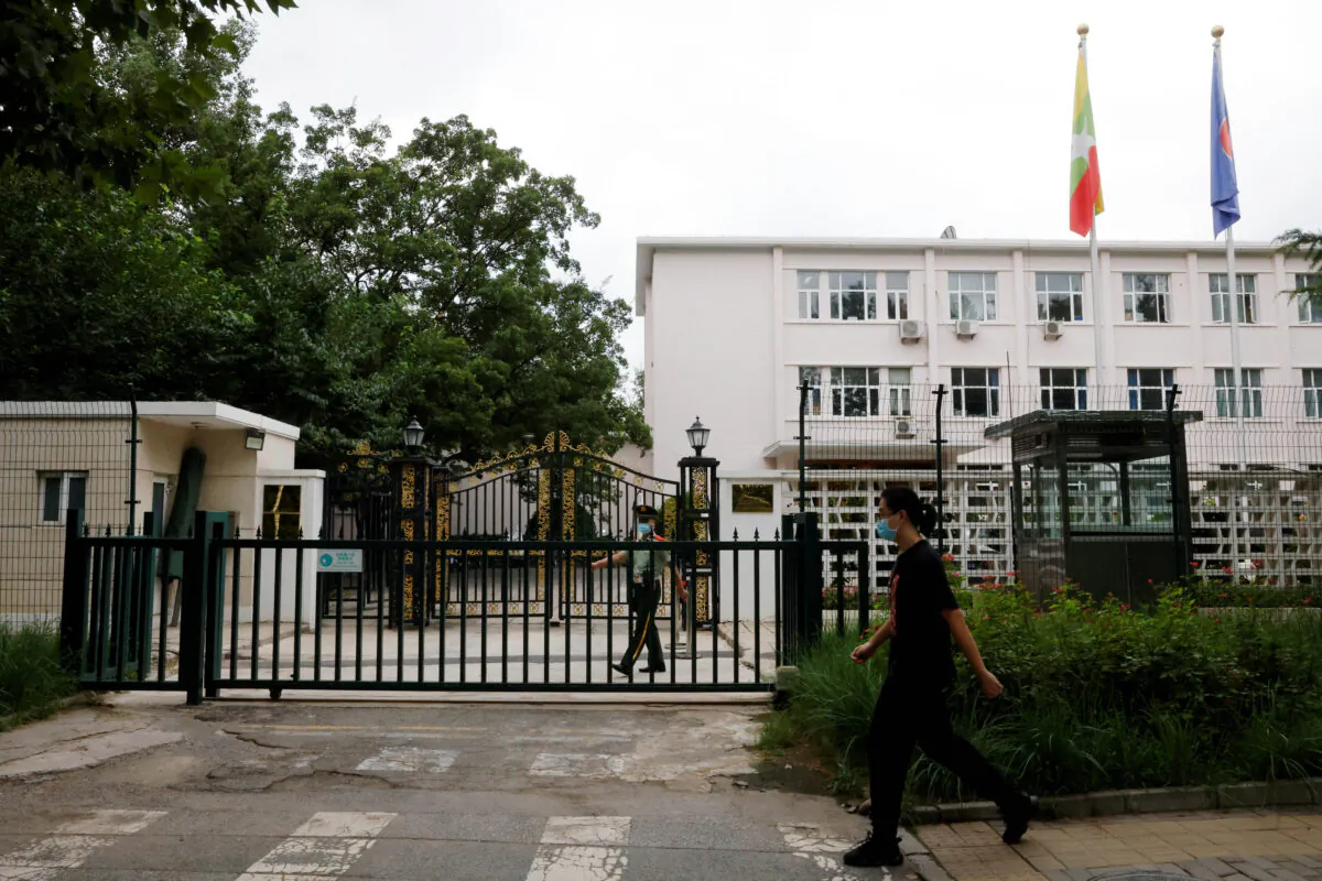 A man walks past a paramilitary police officer keeping watch outside the Burmese embassy in Beijing on Aug. 8, 2022. (Carlos Garcia Rawlins/Reuters)
