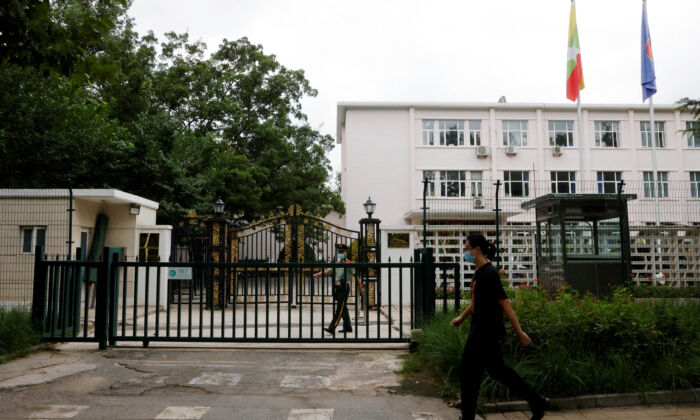 A man walks past a paramilitary police officer keeping watch outside the Burmese embassy in Beijing on Aug. 8, 2022. (Carlos Garcia Rawlins/Reuters)