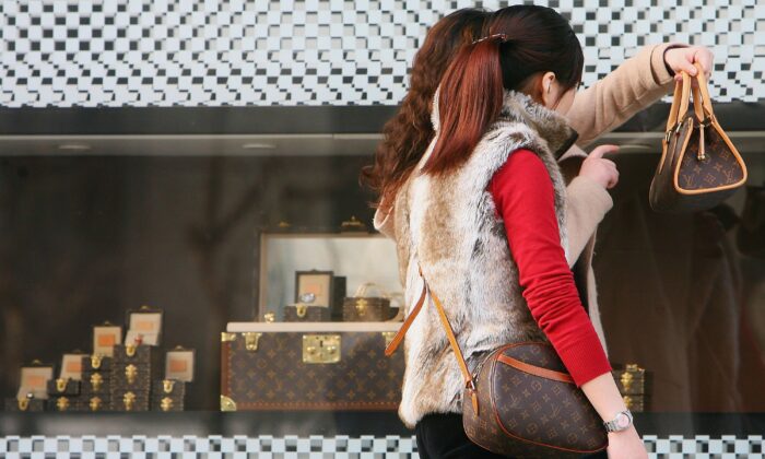 Chinese Women view the bags they bought at a Louis Vuitton flagship store in Shanghai, China, on March 10, 2006. (China Photos/Getty Images)