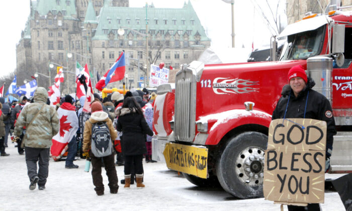 2022 年 2 月 12 日，在渥太华举行的自由车队抗议活动中，一名抗议者在威灵顿街举着牌子。（Noé Chartier/媒体时报）