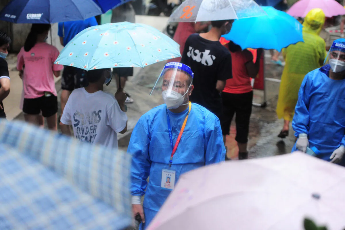A medical worker looks on as residents and tourists line up to undergo COVID-19 tests in Sanya in southern China's Hainan Province on Aug. 8, 2022. (STR/AFP via Getty Images)