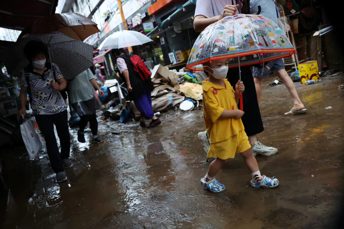 A boy using an umbrella makes his way through a road that was flooded after torrential rain at a traditional market in Seoul, South Korea, on Aug. 9, 2022. (Kim Hong-Ji/Reuters)