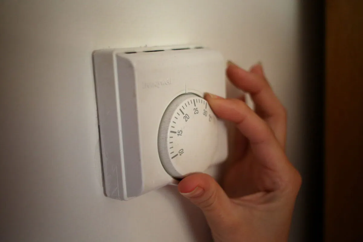 A person adjusts the dial of a thermostat, in a file photo. (Steve Parsons/PA Media)