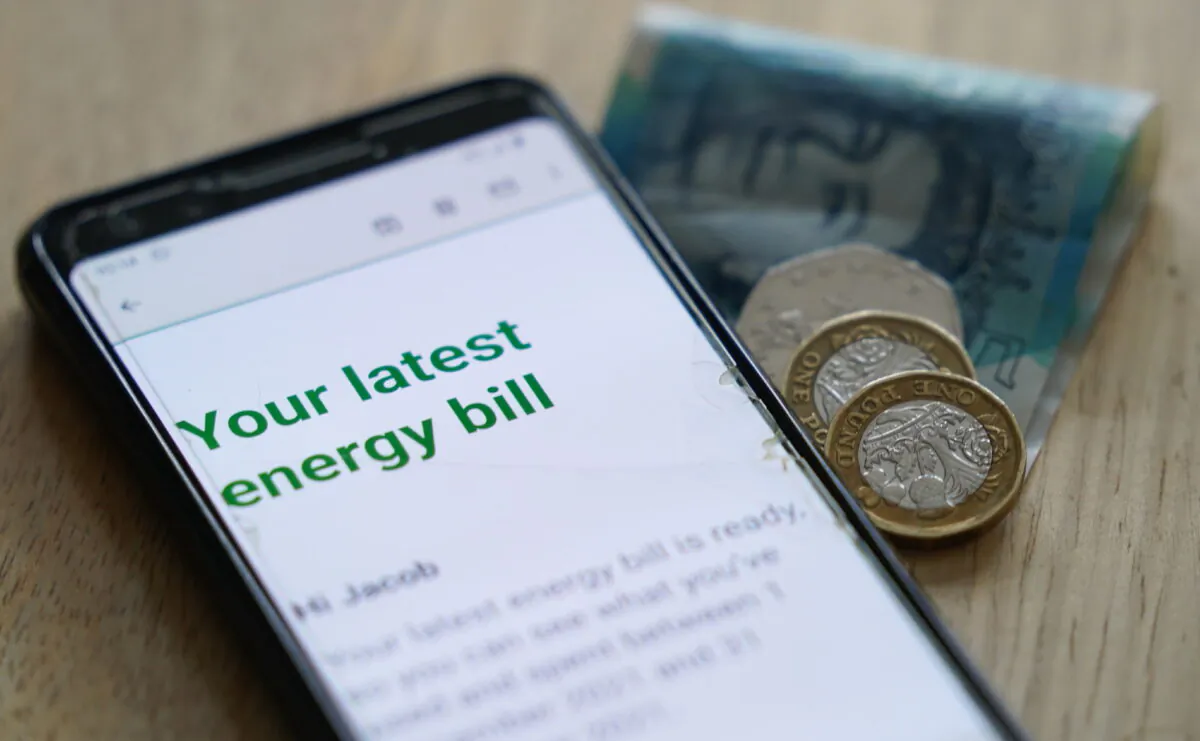 Undated photo showing some cash in sterling with a mobile photo displaying the words "your latest energy bill." (Jacob King/PA Media)