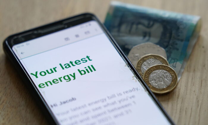 Undated photo showing some cash in Sterling with a mobile photo displaying the words "your latest energy bill." (Jacob King/PA Media)