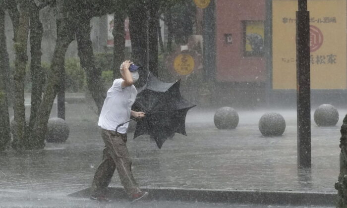 A man is drenched by the rain brought by Tropical Storm Meari, in Hamamatsu, Shizuoka prefecture, central Japan, on Aug. 13, 2022. (Kyodo News via AP)