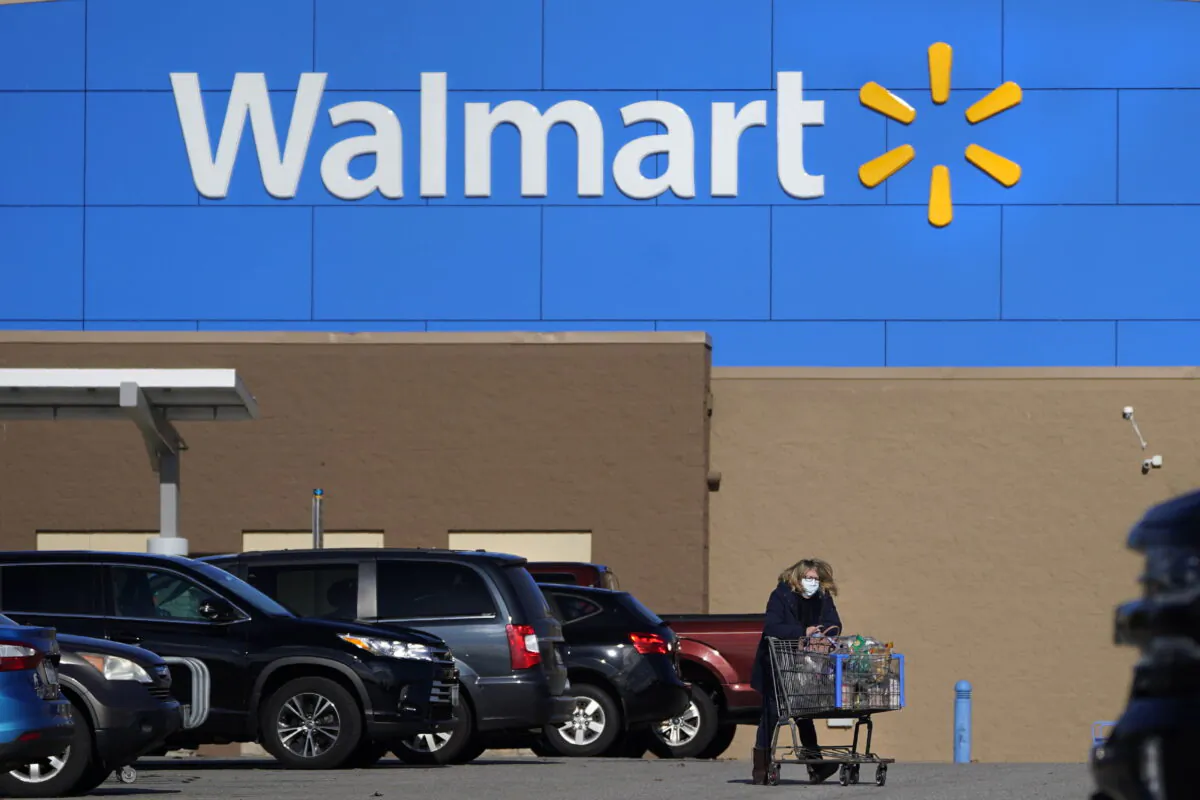 A woman wheels a cart with her purchases out of a Walmart, in Derry, N.H.., on Nov. 18, 2020. (Charles Krupa/AP Photo)