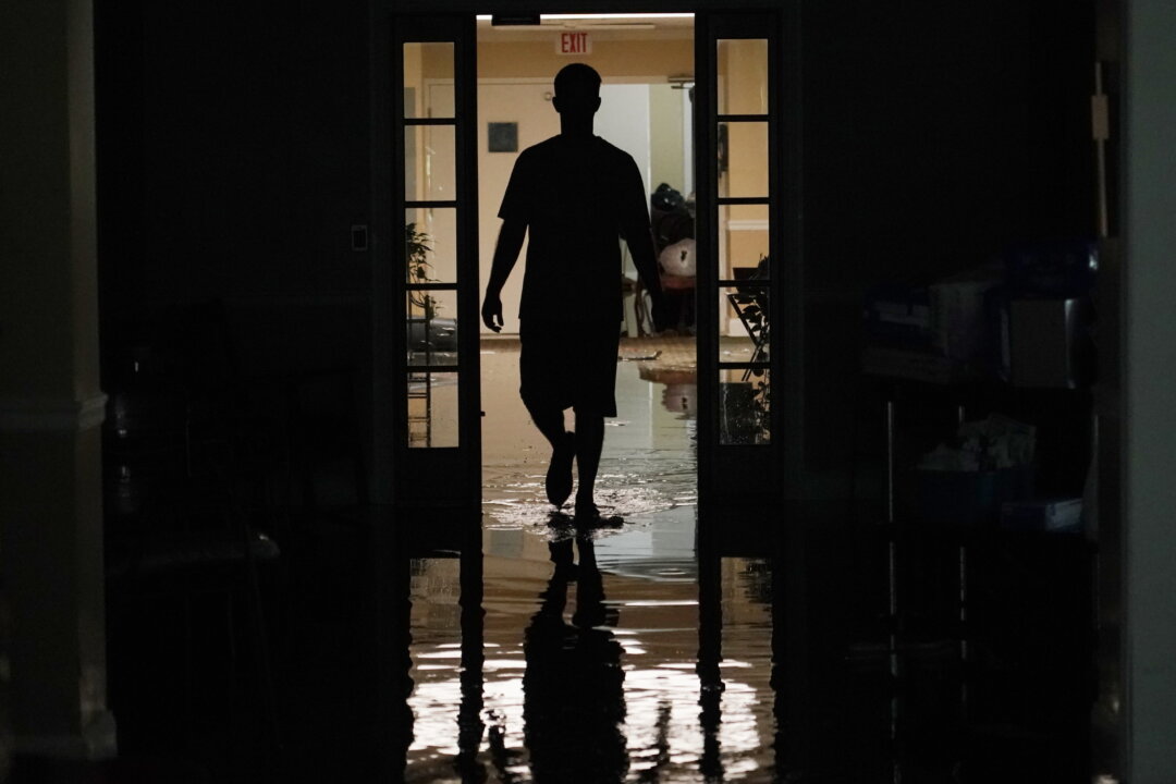 A resident's relative walks through the Peach Tree Village nursing home to collect family possessions from the flooded facility in Brandon, Miss., following a morning of torrential rains, on Aug. 24, 2022. (Rogelio V. Solis/AP Photo)