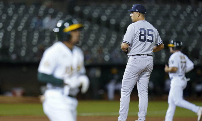 New York Yankees relief pitcher Greg Weissert (85) looks toward home plate after walking Oakland Athletics' Tony Kemp, foreground, to load the bases during the seventh inning of a baseball game in Oakland, Calif., Aug. 25, 2022. (Godofredo A. Vásquez/AP Photo)