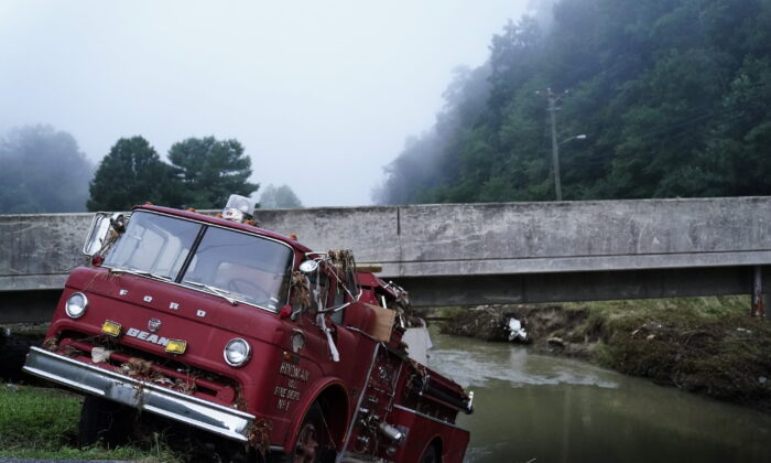 A fire truck is seen hanging over the edge of the water propped against a bridge in Hindman, after massive flooding carried the fire truck towards the water, Ky., on Aug. 3, 2022. (Brynn Anderson/AP Photo)