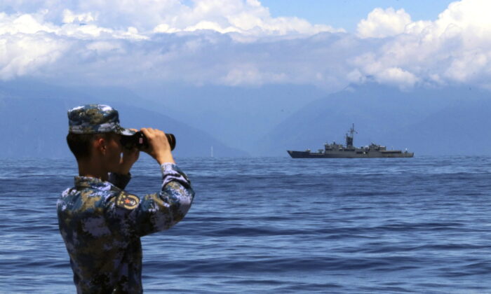 A People's Liberation Army member looks through binoculars during military exercises. Taiwan's frigate, Lan Yang, is seen at the rear on Aug. 5, 2022. (Lin Jian/Xinhua via AP, File)