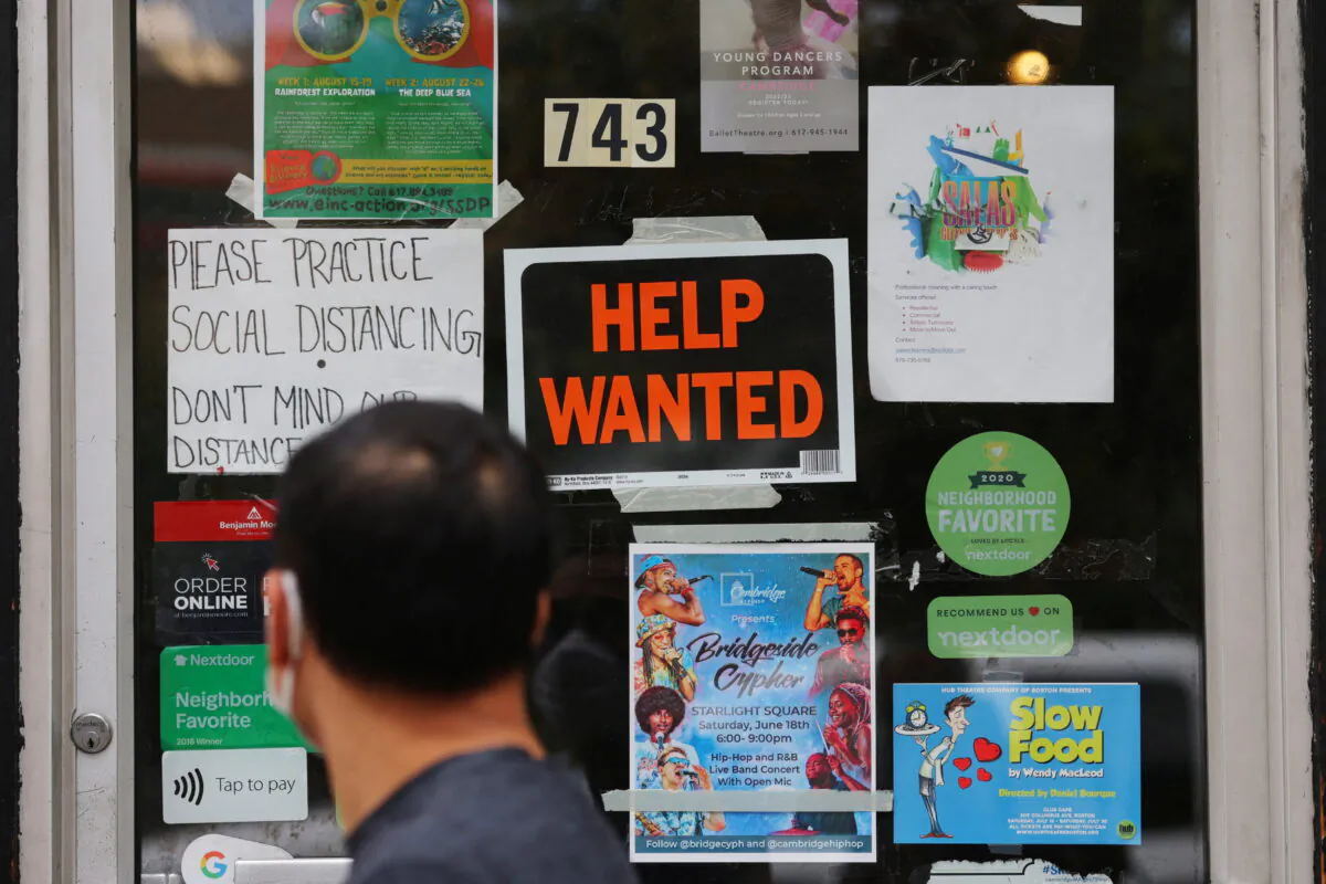 A pedestrian passes a "Help Wanted" sign in the door of a hardware store in Cambridge, Massachusetts, on July 8, 2022. (Brian Snyder/Reuters)