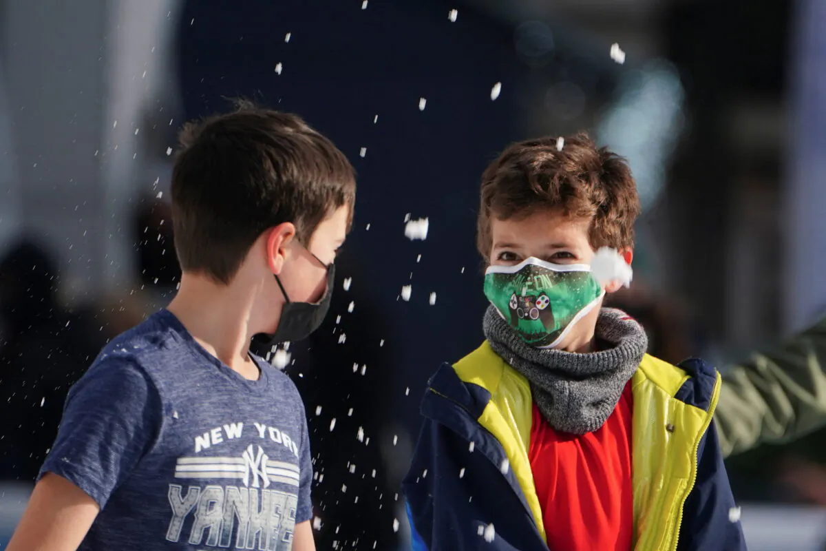Children wearing protective masks toss snow at each other as they skate at Bryant Park, New York, on Jan. 14, 2022. ( REUTERS/Carlo Allegri)