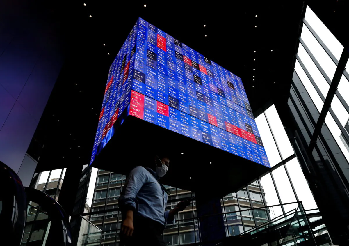 A man walks under an electronic screen showing Japan's Nikkei share price index inside a conference hall in Tokyo, Japan, on June 14, 2022. (Issei Kato/Reuters)
