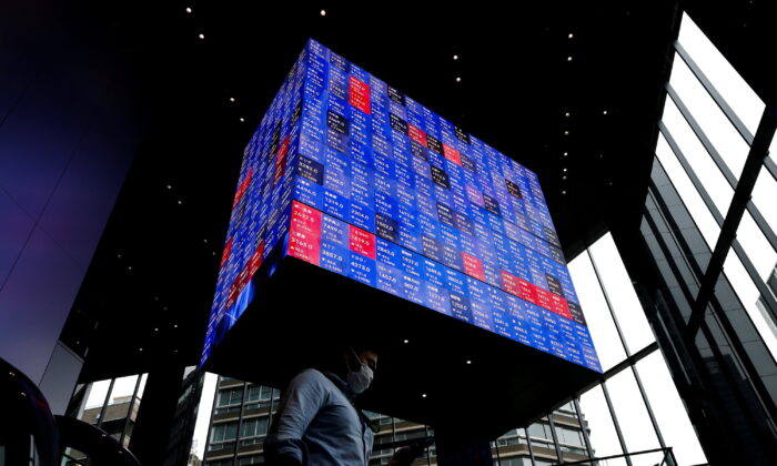 A man walks under an electronic screen showing Japan's Nikkei share price index inside a conference hall in Tokyo, Japan, on June 14, 2022. (Issei Kato/Reuters)