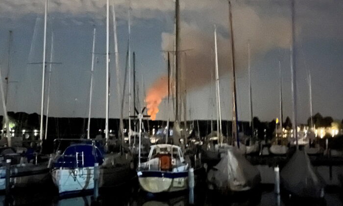 Smoke billows over sailing boats at Lake Wannsee in the harbor of Berlin's suburb Spandau after explosions in a former munitions depot and a wildfire at Grunewald Forest in Berlin, on Aug. 4, 2022. (Reuters/Stringer)