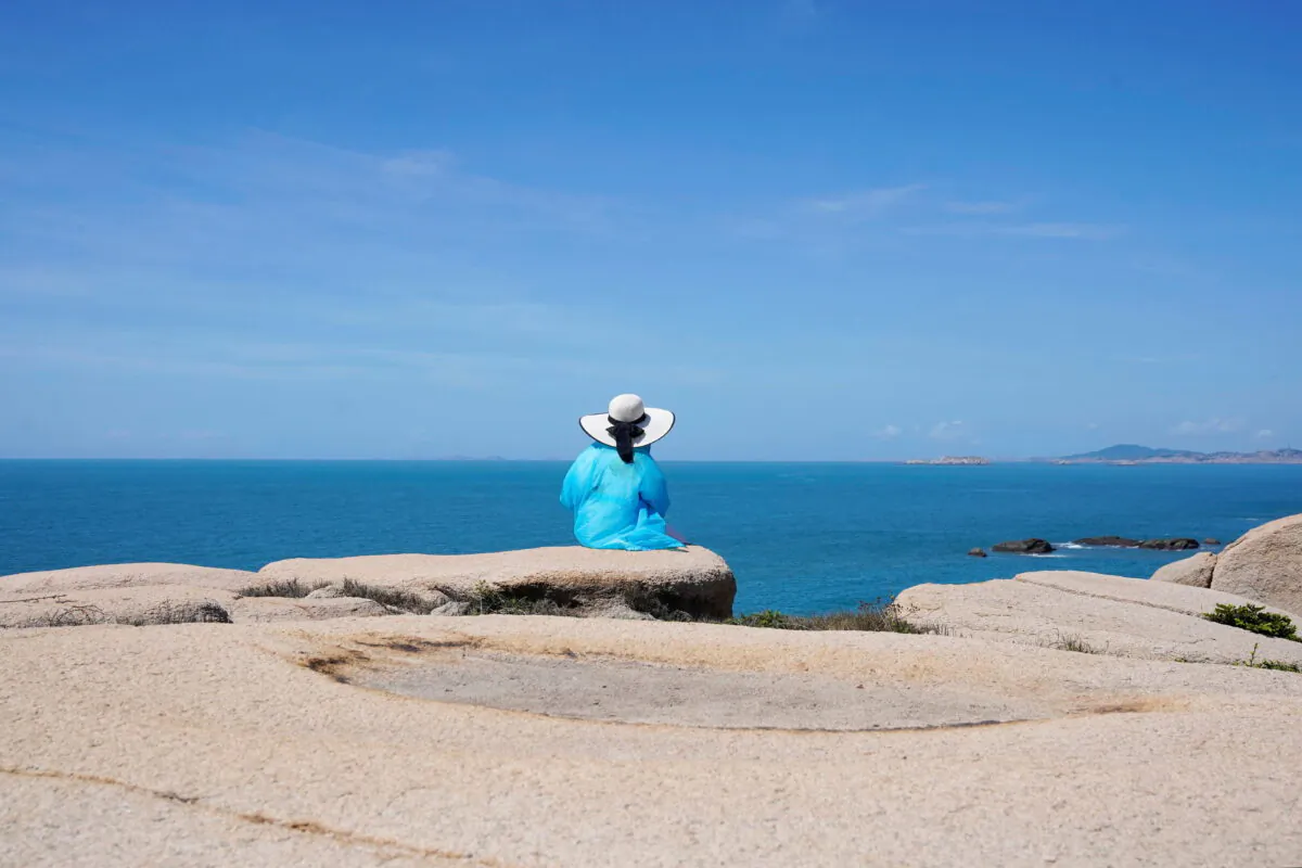 A tourist sits facing the Taiwan Strait at the 68-nautical-mile scenic spot, one of mainland China's closest points to the island of Taiwan, in Pingtan island, Fujian province, China, on Aug. 5, 2022. (Aly Song/Reuters)