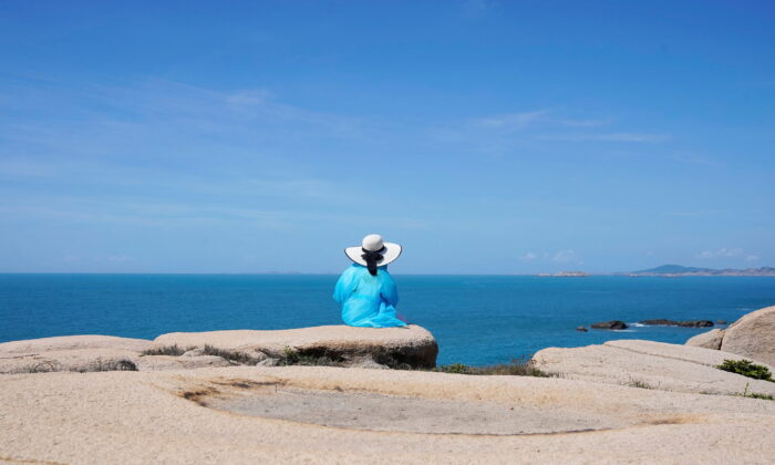 A tourist sits facing the Taiwan Strait at the 68-nautical-mile scenic spot, one of mainland China's closest points to the island of Taiwan, in Pingtan island, Fujian province, China, on Aug. 5, 2022. (Aly Song/Reuters)