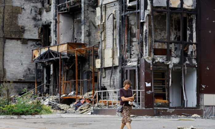 A woman walks near a building damaged in the course of Ukraine-Russia conflict in the southern port city of Mariupol, Ukraine, on Aug. 21, 2022. (Alexander Ermochenko/Reuters)