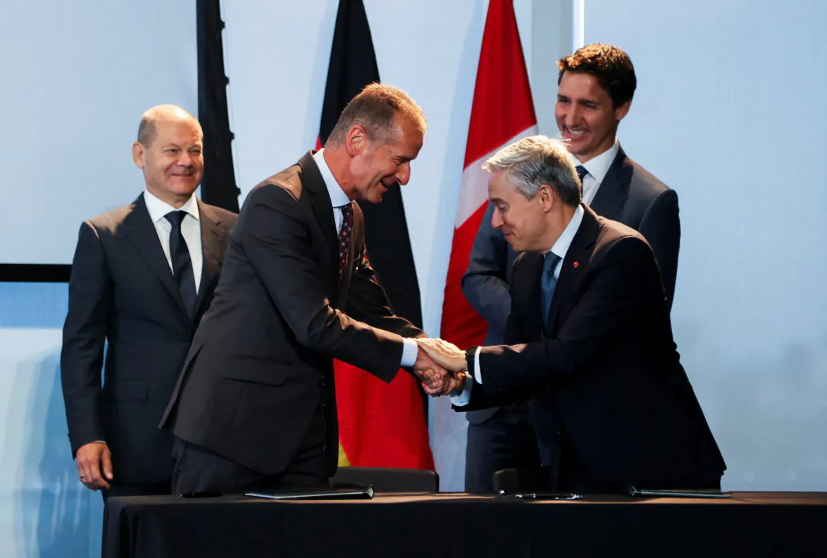 Dr. Herbert Diess, CEO and Chairman of the Board of Management of Volkswagen AG, and Canada's Minister of Innovation, Science and Industry Francois-Philippe Champagne shake hands during the signing of a memorandum of understanding as Canada's Prime Minister Justin Trudeau and Germany's Chancellor Olaf Scholz look on, at the Canada-Germany Business Forum, in Toronto, Canada, on Aug. 23, 2022. (Carlos Osorio/Reuters)
