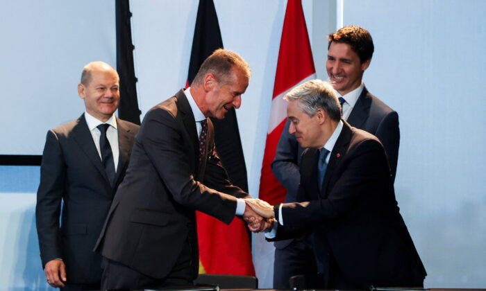 Dr. Herbert Diess, CEO and Chairman of the Board of Management of Volkswagen AG, and Canada's Minister of Innovation, Science and Industry Francois-Philippe Champagne shake hands during the signing of a memorandum of understanding as Canada's Prime Minister Justin Trudeau and Germany's Chancellor Olaf Scholz look on, at the Canada-Germany Business Forum, in Toronto, Canada, on Aug. 23, 2022. (Carlos Osorio/Reuters)
