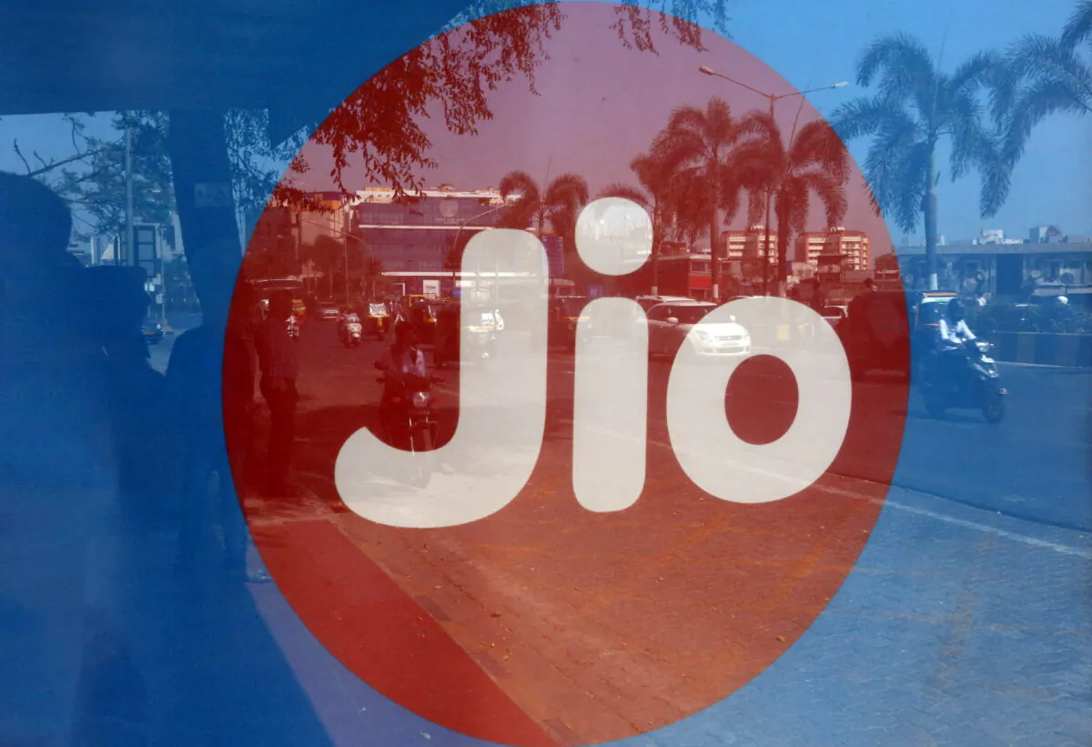 Commuters are reflected on an advertisement of Reliance Industries' Jio telecoms unit, at a bus stop in Mumbai, India on Feb. 21, 2017. (Shailesh Andrade/Reuters)