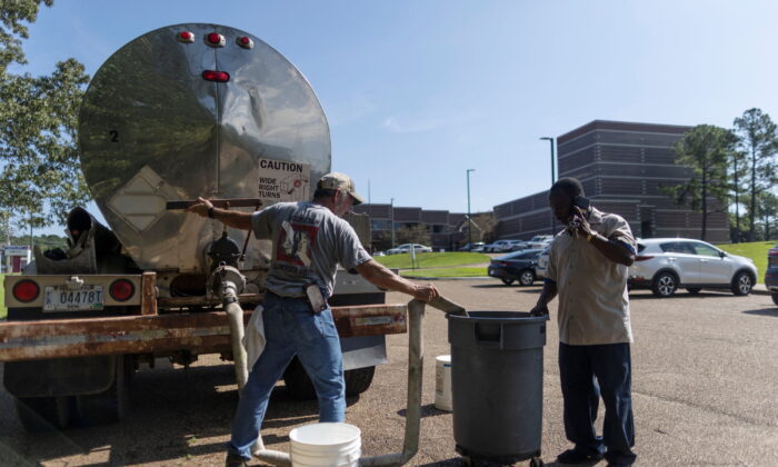 2022 年 8 月 31 日，在密西西比州杰克逊市的 Forest Hill 高中，一名当地工人将水倒入一个桶中，用于冲洗厕所。（Carlos Barria/路透社）