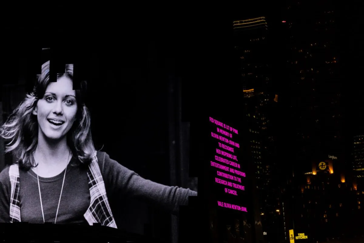 Federation Square is lit up pink as a tribute to Olivia Newton-John, in Melbourne, Tuesday, August 9, 2022. Olivia Newton-John, the singing superstar who won viewers' hearts as Sandy in the blockbuster musical Grease, has died aged 73 at her home in California. (AAP Image/Diego Fedele)