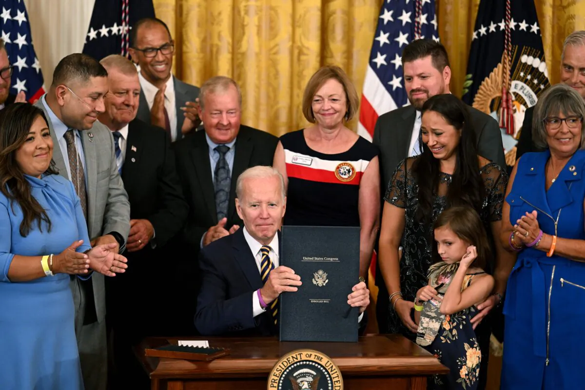 U.S. President Joe Biden displays the enrolled bill after signing the PACT Act of 2022 into law during a ceremony in the East Room of the White House in Washington on Aug. 10, 2022. (Jim Watson/AFP via Getty Images)
