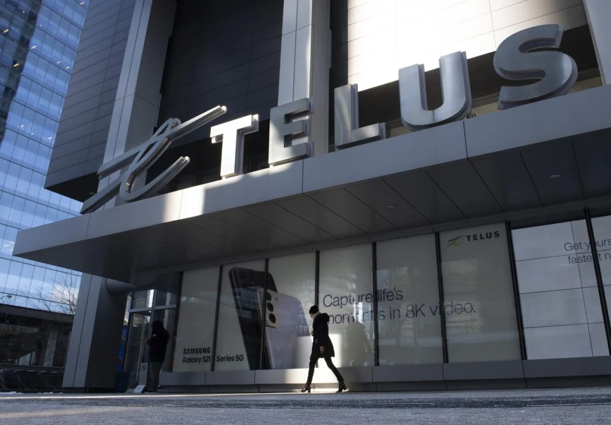 A woman walks past the Telus head office in Toronto on Feb. 11, 2021. (Frank Gunn/The Canadian Press)