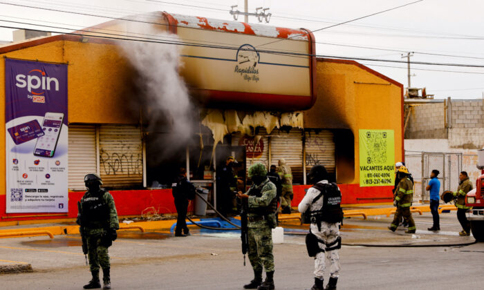 Security forces stand outside a convenience store that was burned by unknown attackers, in a simultaneous attack of fires in different parts of the city, in Ciudad Juarez, Mexico, on Aug. 11, 2022. (Jose Luis Gonzalez/Reuters)