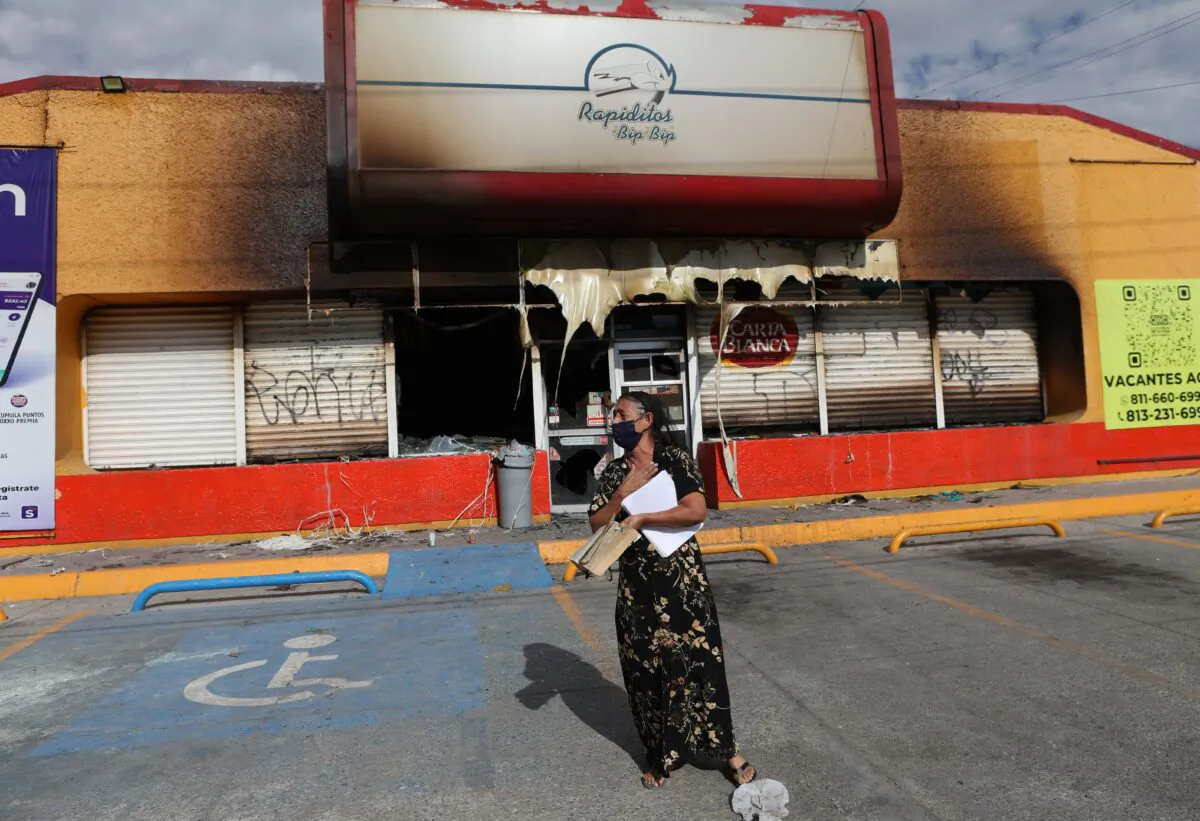 A woman stands in front of the building where unknown persons burnt down shops in Ciudad Juarez, state of Chihuahua, Mexico, on Aug. 12, 2022. (Herika Martinez/AFP via Getty Images)