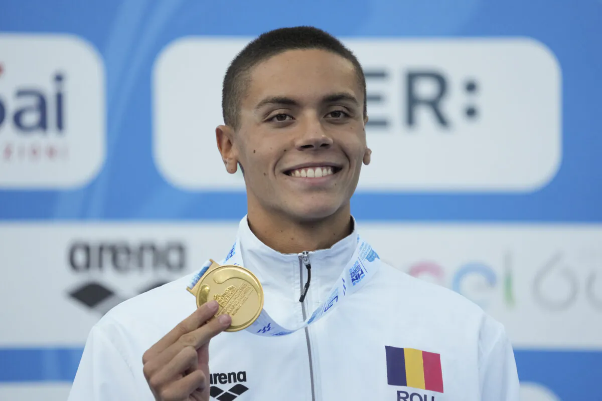 First placed Romania's David Popovici celebrates on the podium of the men's 100m freestyle final at the European swimming championships in Rome on Aug. 13, 2022. (Andrew Medichini/AP Photo)