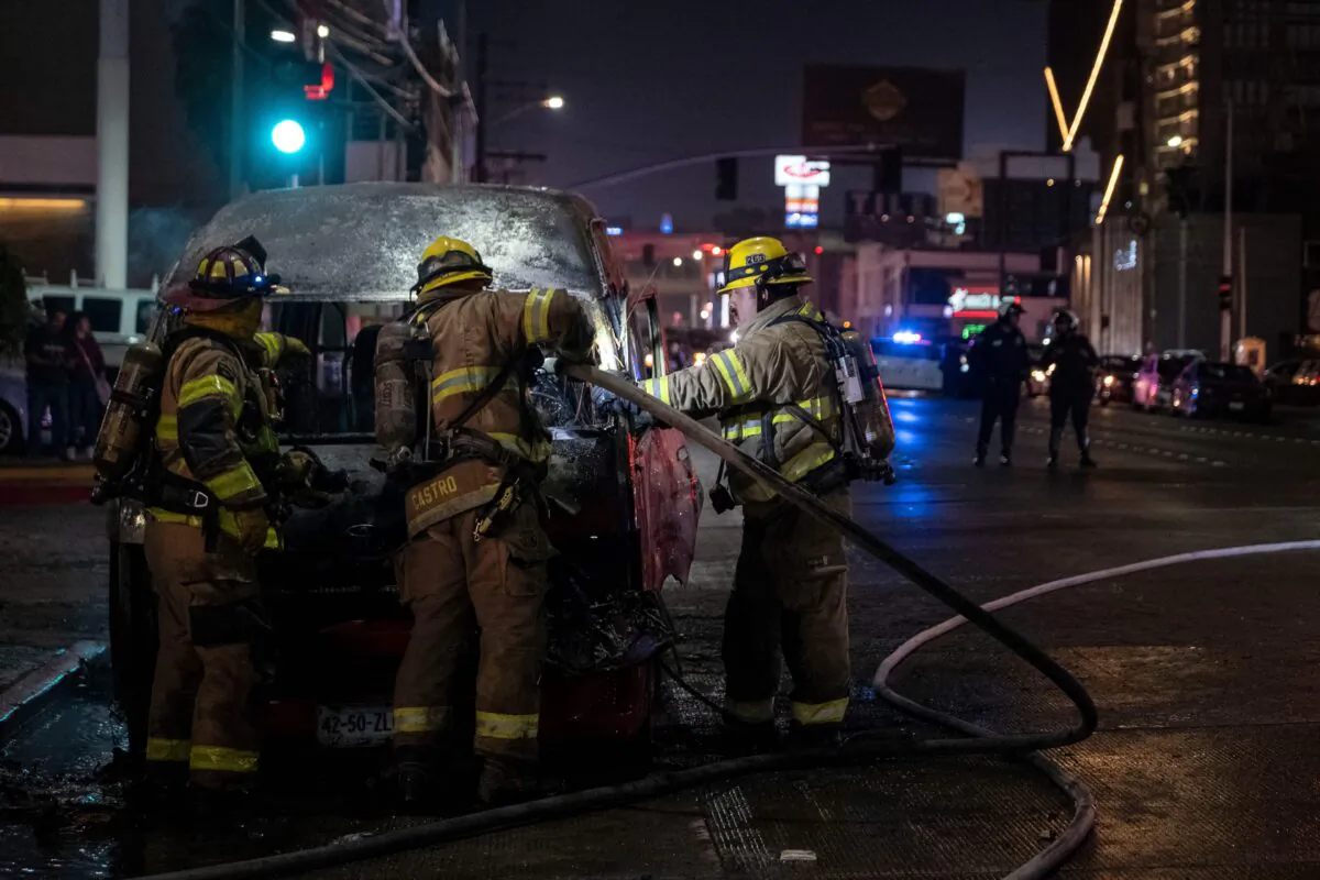 Firefighters work at the scene of a burnt collective transport vehicle after it was set on fire by unidentified individuals in Tijuana, Baja California state, Mexico, on Aug. 12, 2022. (Guillermo Arias/AFP via Getty Images)