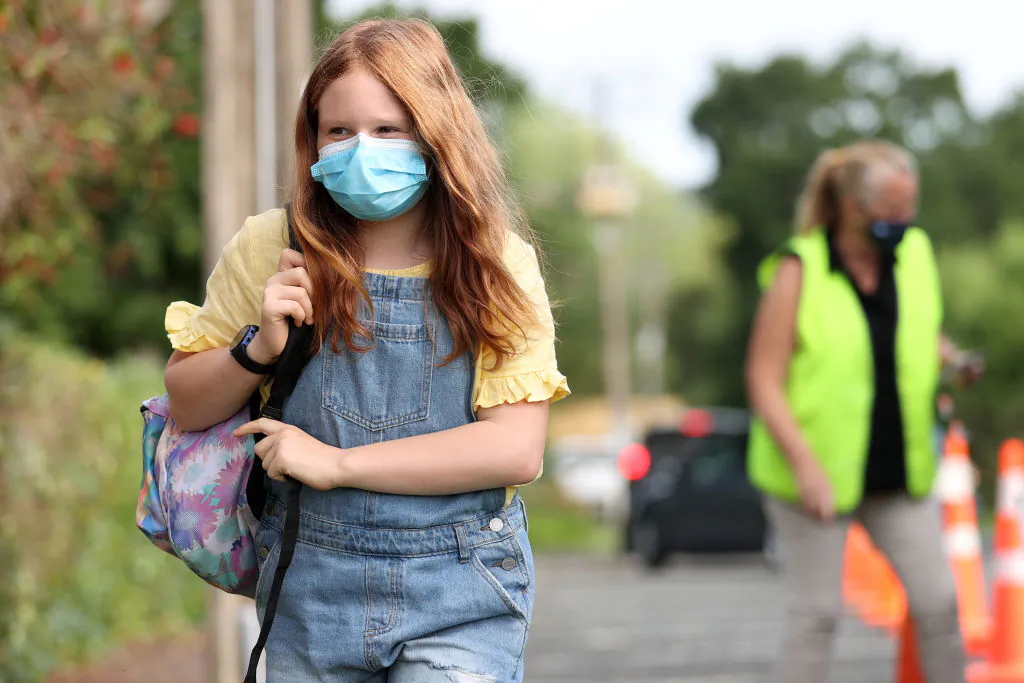 A girl arrives at school as children are welcomed by their principal on their first day at school after lockdowns ended in Auckland, New Zealand, on Nov. 17, 2021. (Fiona Goodall/Getty Images)