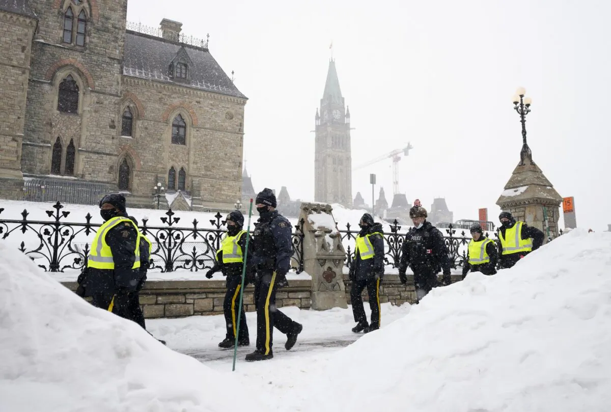 Police officers walk pass the Parliament buildings after a protest in Ottawa on Feb. 20, 2022. (The Canadian Press/Adrian Wyld)
