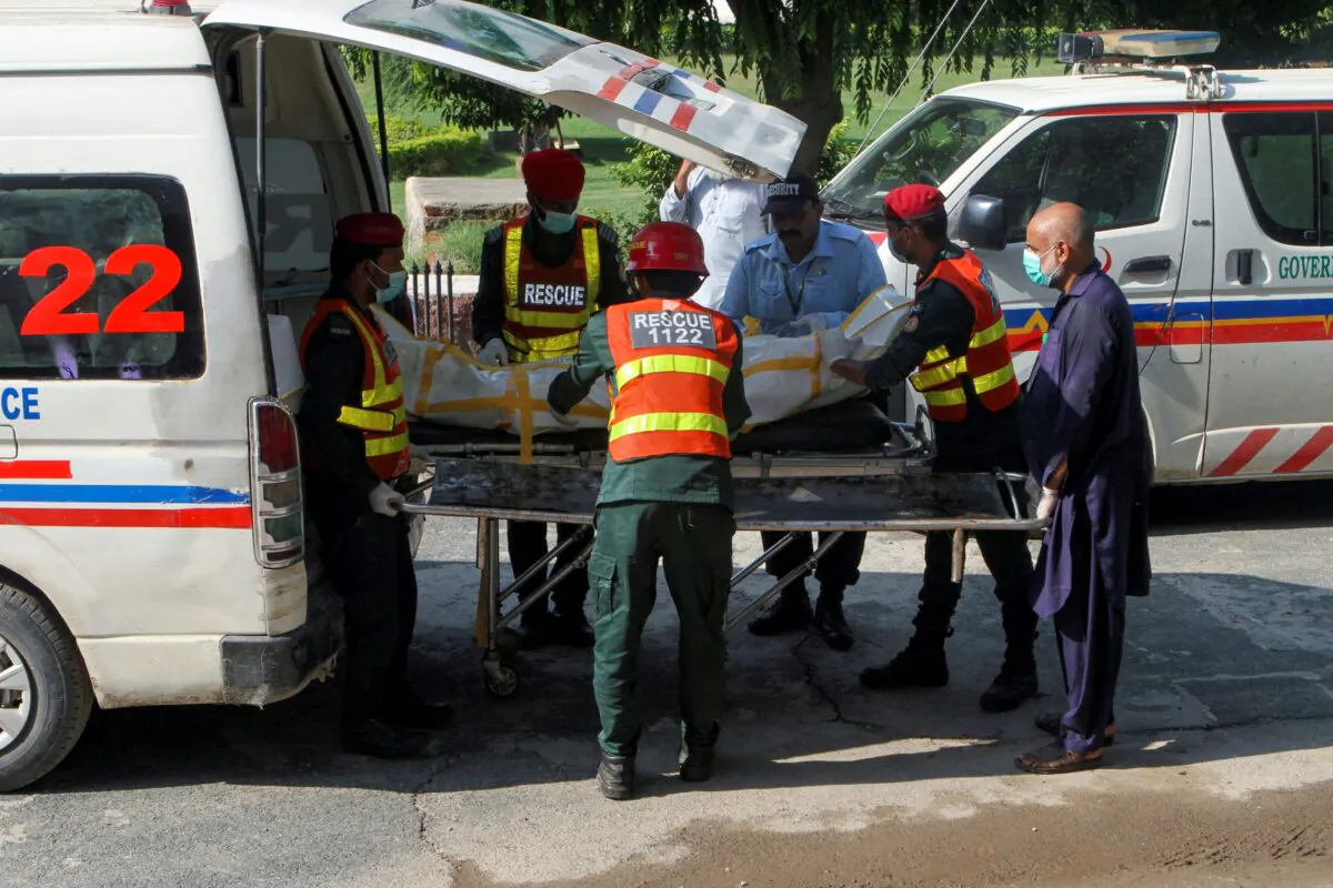 Rescue workers shift a body of a victim, who was killed after a passenger bus and an oil tanker collided and caught fire, from an ambulance outside Nishtar Hospital in Multan, Pakistan on Aug.16, 2022. (Arshad Raza Zaidi/Reuters)