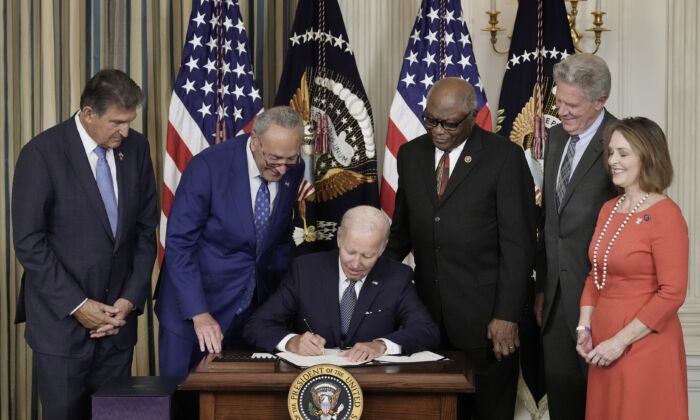 President Joe Biden signs the Inflation Reduction Act as Democrat lawmakers look on at the White House on Aug. 16, 2022. (Drew Angerer/Getty Images)