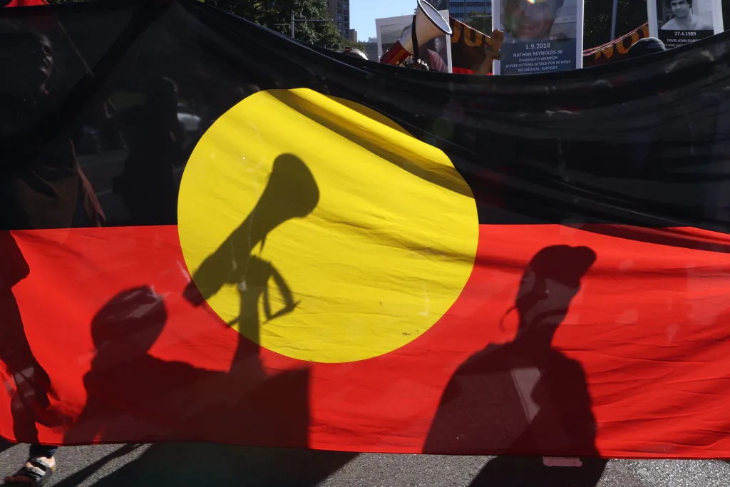 Protesters are seen through an Aboriginal flag during a rally in Sydney, Australia, on April 10, 2021. (David Gray/Getty Images)