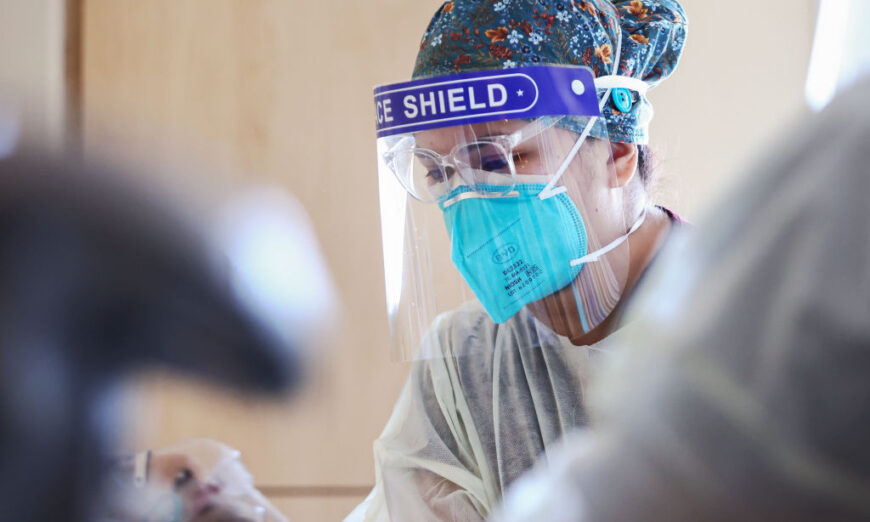 注册护士 Elle Lauron 于 2021 年 7 月 30 日在加利福尼亚州洛杉矶 Mission Hills 社区的 Providence Holy Cross 医疗中心的临时病房中照顾一名 COVID-19 患者。（Mario Tama/Getty Images）
