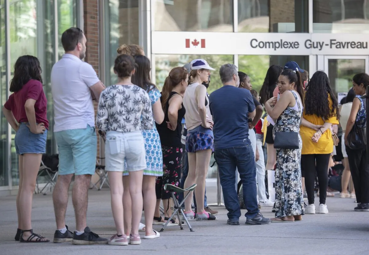 People line up outside the Guy Favreau federal building while waiting to apply for a passport in Montreal, June 26, 2022. (The Canadian Press/Graham Hughes)