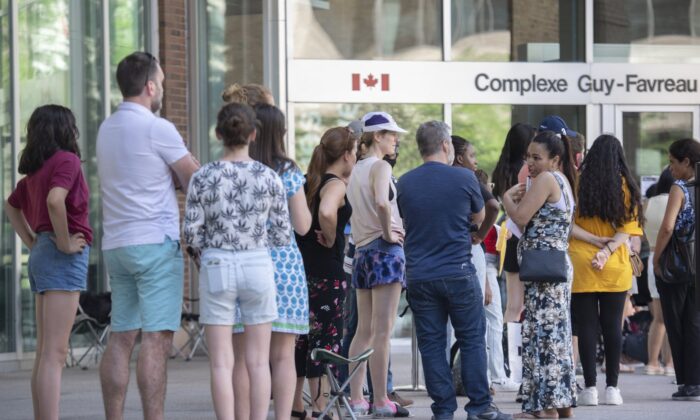 People line up outside the Guy Favreau federal building while waiting to apply for a passport in Montreal, June 26, 2022. (The Canadian Press/Graham Hughes)