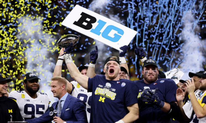 Aidan Hutchinson #97 of the Michigan Wolverines celebrates with the trophy after the Michigan Wolverines defeated the Iowa Hawkeyes 42-3 to win the Big Ten Championship game at Lucas Oil Stadium in Indianapolis, on December 4, 2021. (Dylan Buell/Getty Images)