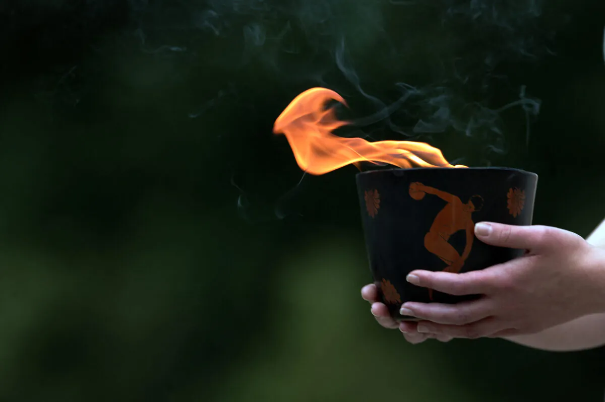 An urn carrying the Olympic Flame held by a priestess in a reenactment of lighting ceremony in ancient Olympia where the Olympic Games were born in 776 B.C.  The Olympic flame was lit in Ancient Olympia in Greece, in a solemn ceremony filled with mystery and tradition. (Aris Messinis/AFP via Getty Images)