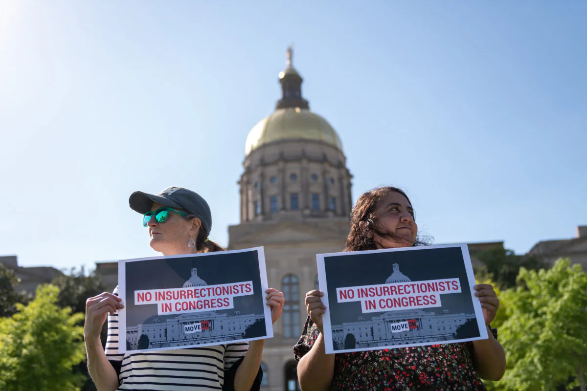 Georgians hold signs in front of the Georgia State Capitol in support of the challenge to Marjorie Taylor Greene’s qualification for the ballot under the insurrection clause of the 14th Amendment, in Atlanta, on April 21, 2022. (Derek White/Getty Images for MoveOn)