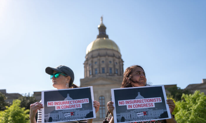 Georgians hold signs in front of the Georgia State Capitol in support of the challenge to Marjorie Taylor Greene’s qualification for the ballot under the insurrection clause of the 14th Amendment, in Atlanta, on April 21, 2022. (Derek White/Getty Images for MoveOn)
