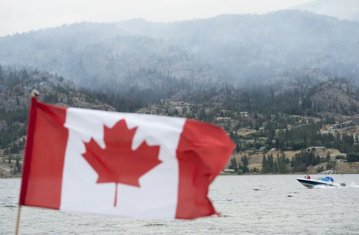 Boaters enjoy Skaha Lake as a wildfire burns in the background in Penticton, B.C. Aug. 20, 2020. (The Canadian Press/Jonathan Hayward)