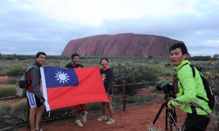 Taiwanese tourists take a picture with the Taiwanese flag at the sunset carpark at Uluru, Australia, on Oct. 25, 2010. (AAP Image/Dean Lewins)