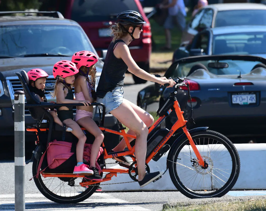 A woman takes three children on a bike ride in Vancouver on June 29, 2021. (Don MacKinnon/AFP via Getty Images)