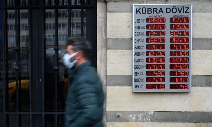 A man walks in front of a screen showing rates against Turkish lira near a currency exchange agency at Kaarakoy in Istanbul on Dec.16, 2021 in Istanbul. (Ozan Kose/AFP via Getty Images)